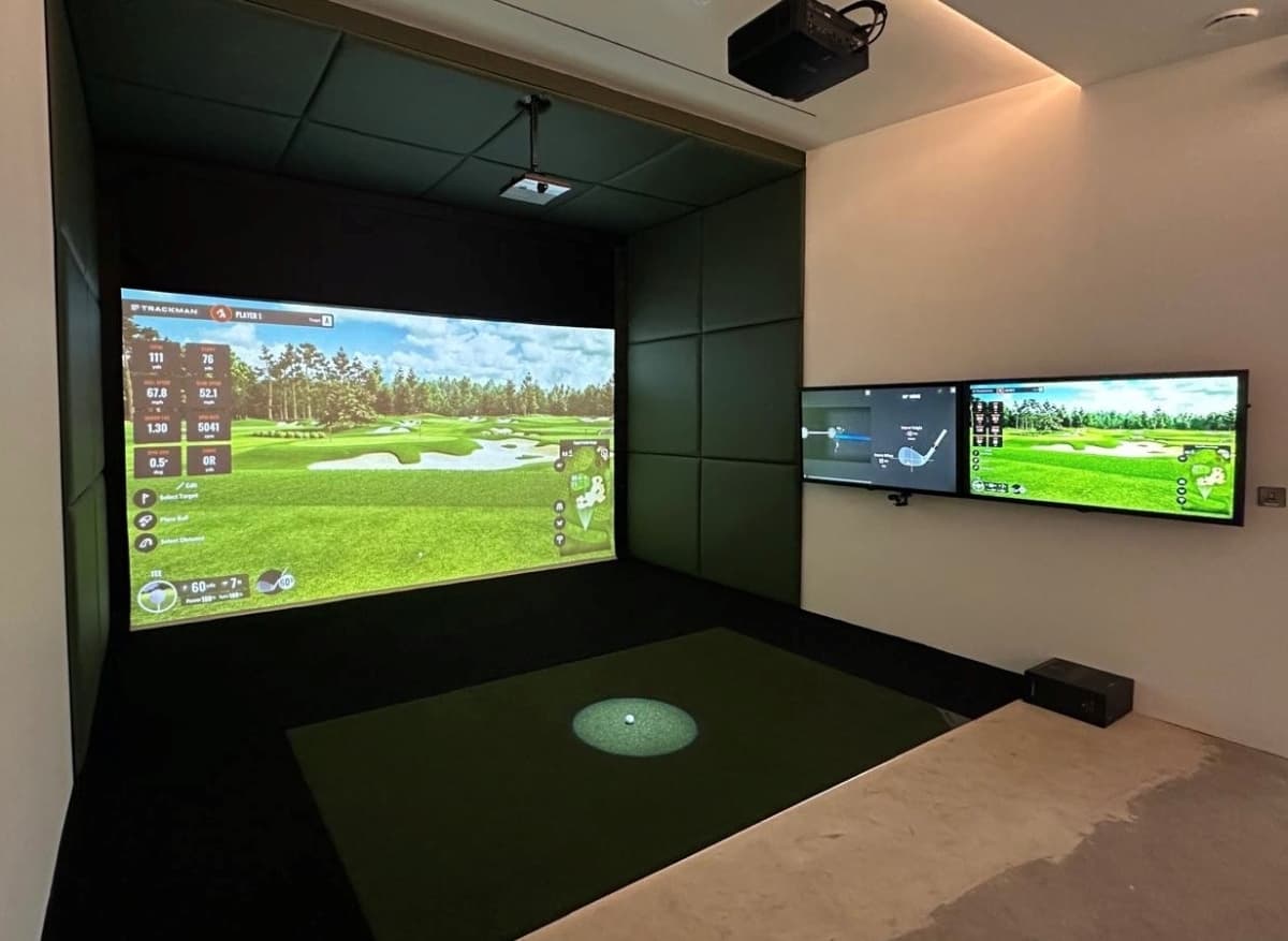 A golfer mid-swing in a premium indoor Foresight simulator bay at The Clubhouse Golf Sims